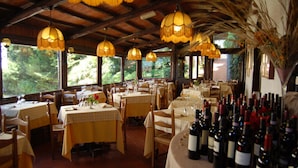 A restaurant with multiple tables set for dining, surrounded by large windows offering a view of greenery. - Balletti Park Hotel (Viterbo)