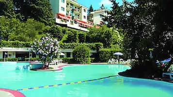 Une piscine entourée d’une végétation luxuriante et un bâtiment doté de nombreux balcons.