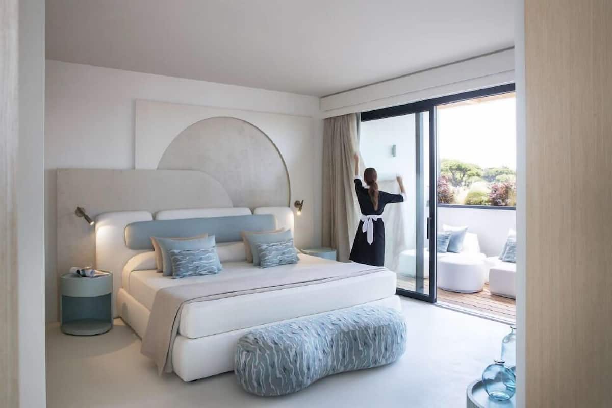A modern bedroom with a large bed, bedside tables, and a view of the outdoors.