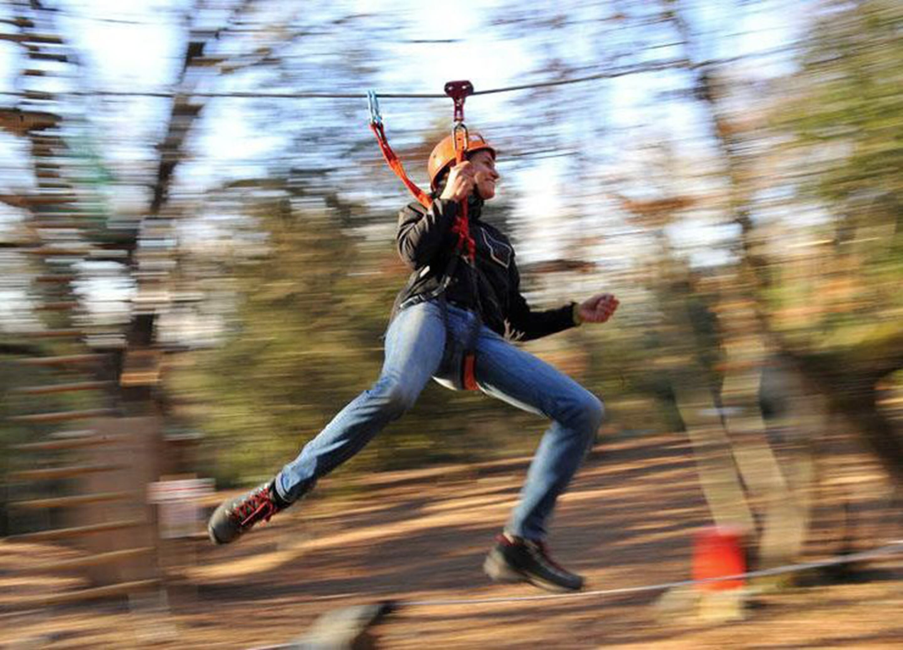 A person ziplining through a forested area.