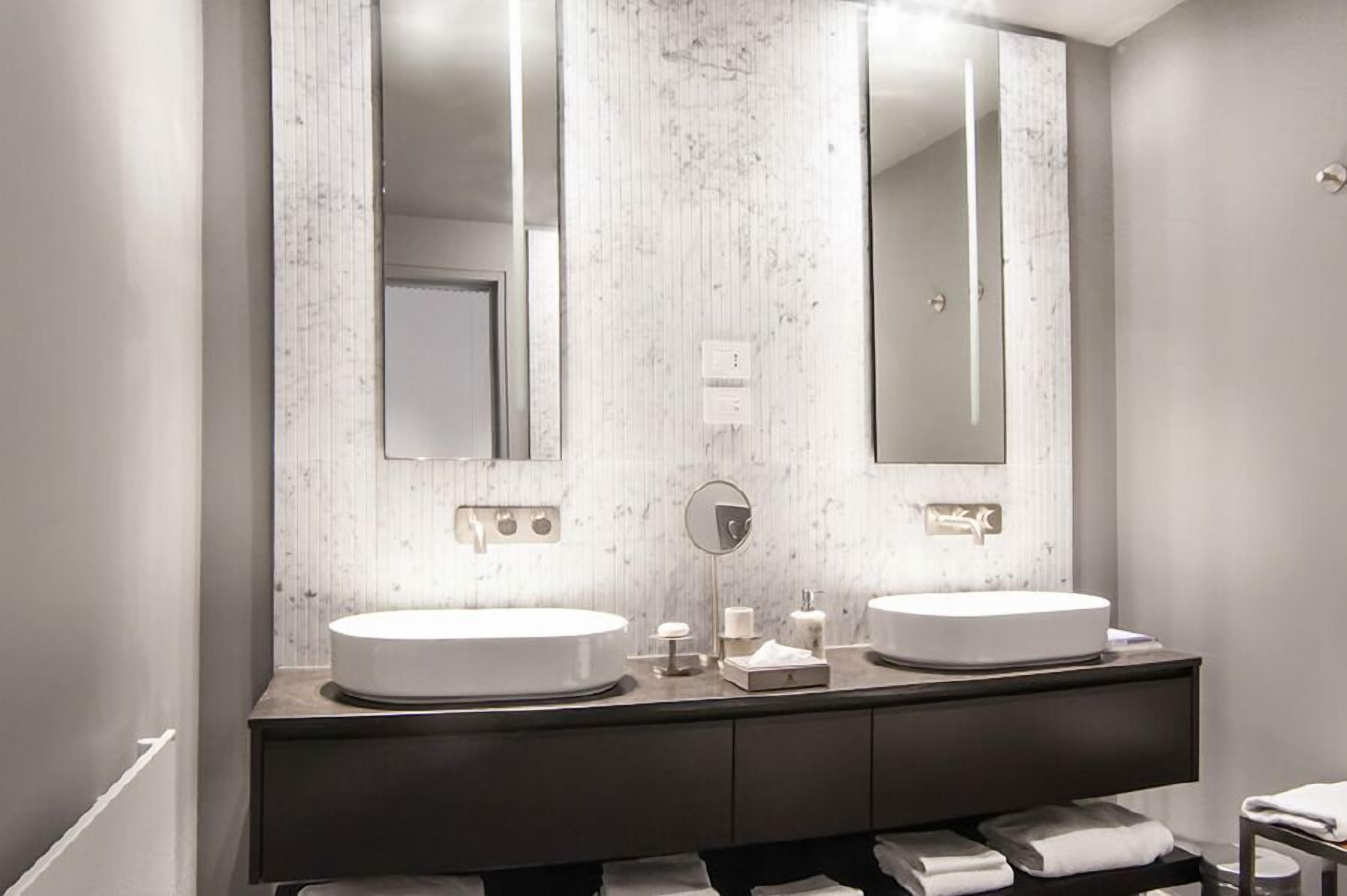 A modern bathroom with two round sinks, a large mirror, and a dark wooden vanity.