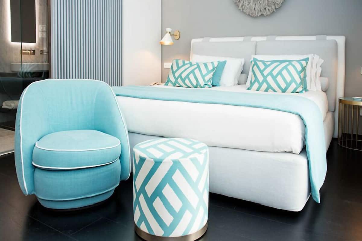 A modern bedroom with a bed, a blue chair, and a matching ottoman.