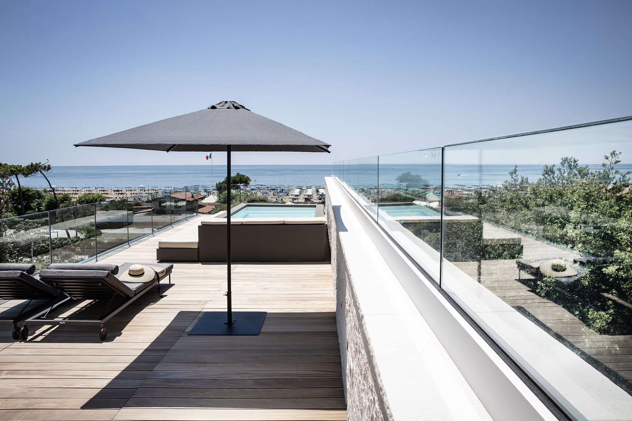 Una terraza en la azotea con piscina, sillas de descanso y vistas al mar.