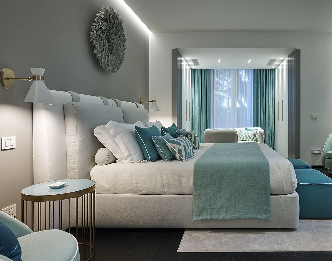 Una camera da letto moderna con un letto grande, un comodino, una sedia e vista sull'esterno attraverso una finestra con tende.