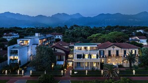 Um hotel de vários andares com design moderno, com varandas e vista para montanhas ao longe.