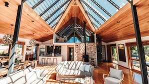 A spacious interior with a high ceiling, wooden flooring, and a large skylight. - Eagles Nest (Russell)