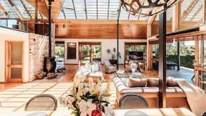 A spacious living area with a high ceiling, large windows, and a fireplace. - Eagles Nest (Russell)
