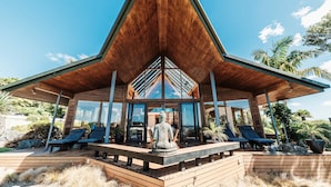 A modern villa with a wooden deck, lounge chairs, and a statue. - Eagles Nest (Russell)