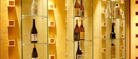 Una variedad de botellas, presumiblemente bebidas alcohólicas, dispuestas en estantes dentro de una habitación bien iluminada con una pared con textura.