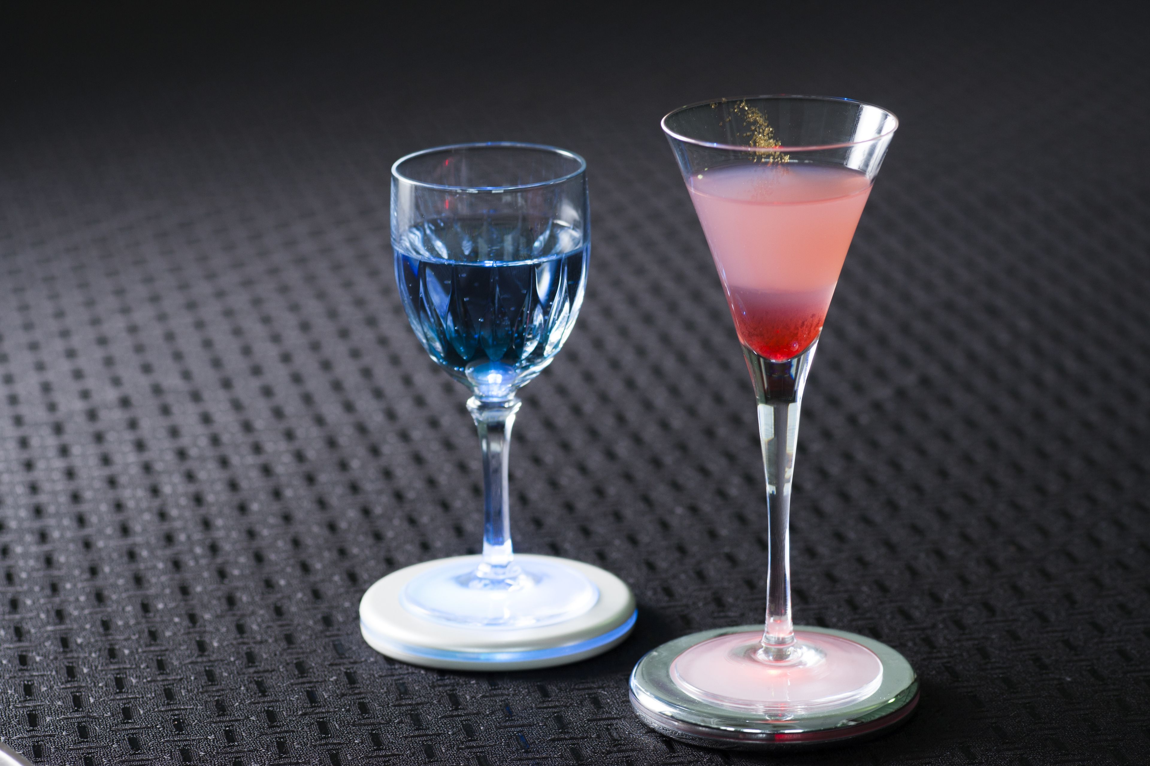 Dos vasos de bebidas de colores distintos sobre una superficie con textura.