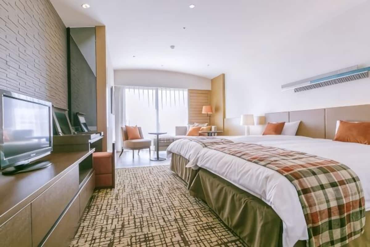 A hotel room with a bed, a TV, a desk, and a chair.