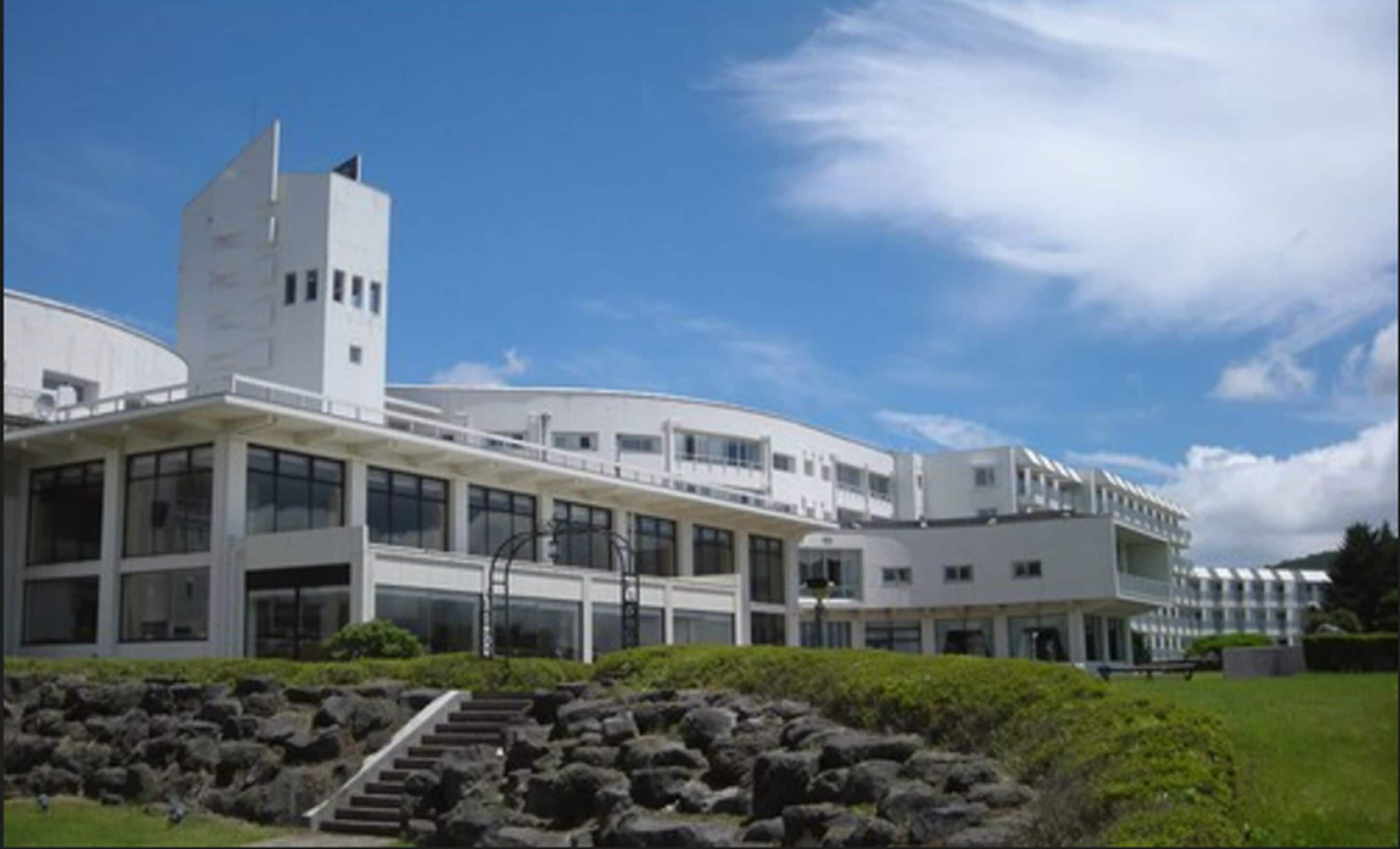 A modern building with a curved facade, multiple windows, and a central tower.