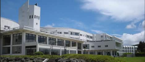 A modern building with a curved facade, multiple windows, and a central tower.