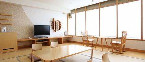 A modern room with tatami mats, a TV, a wooden table, and chairs.