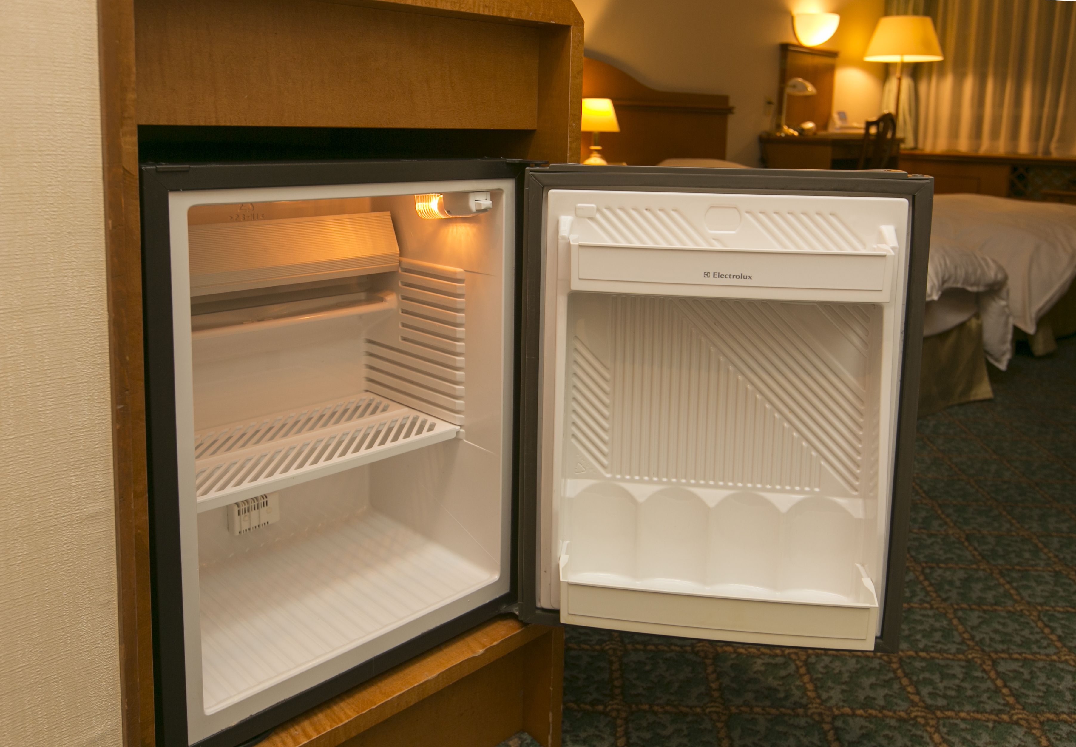 An open hotel mini-fridge with a freezer compartment on the left and a refrigerator compartment on the right.