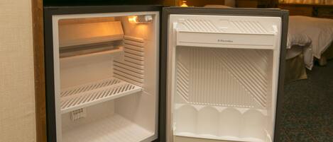 An open hotel mini-fridge with a freezer compartment on the left and a refrigerator compartment on the right.