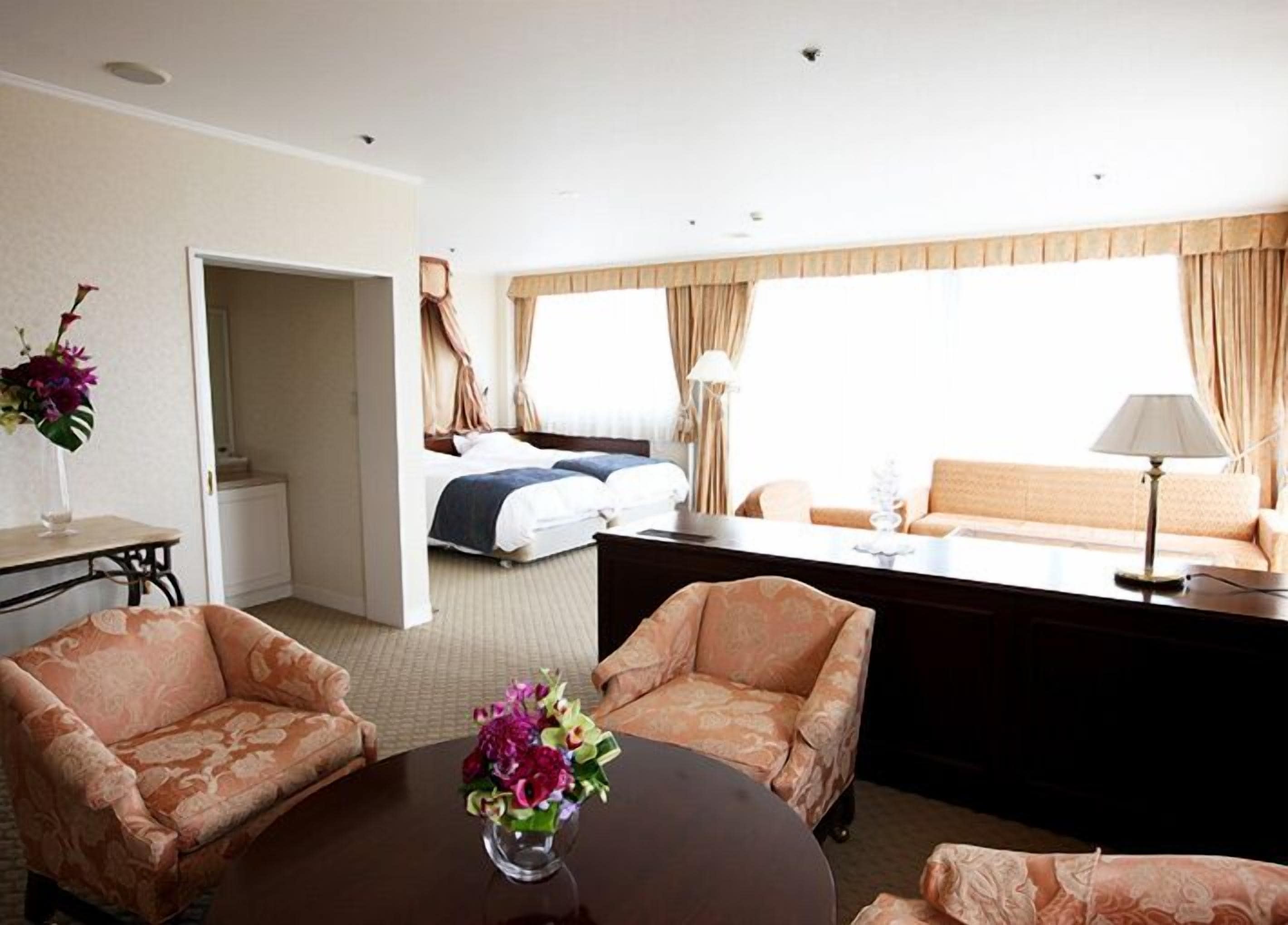 A hotel room with a bed, two armchairs, a desk, and a sofa.