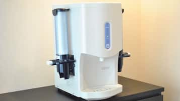 Una máquina de café con dispensador de agua y panel de botones, sobre una encimera oscura.