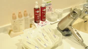 A bathroom counter with various toiletries including bottles of lotion, a hairdryer, and a toothbrush holder.