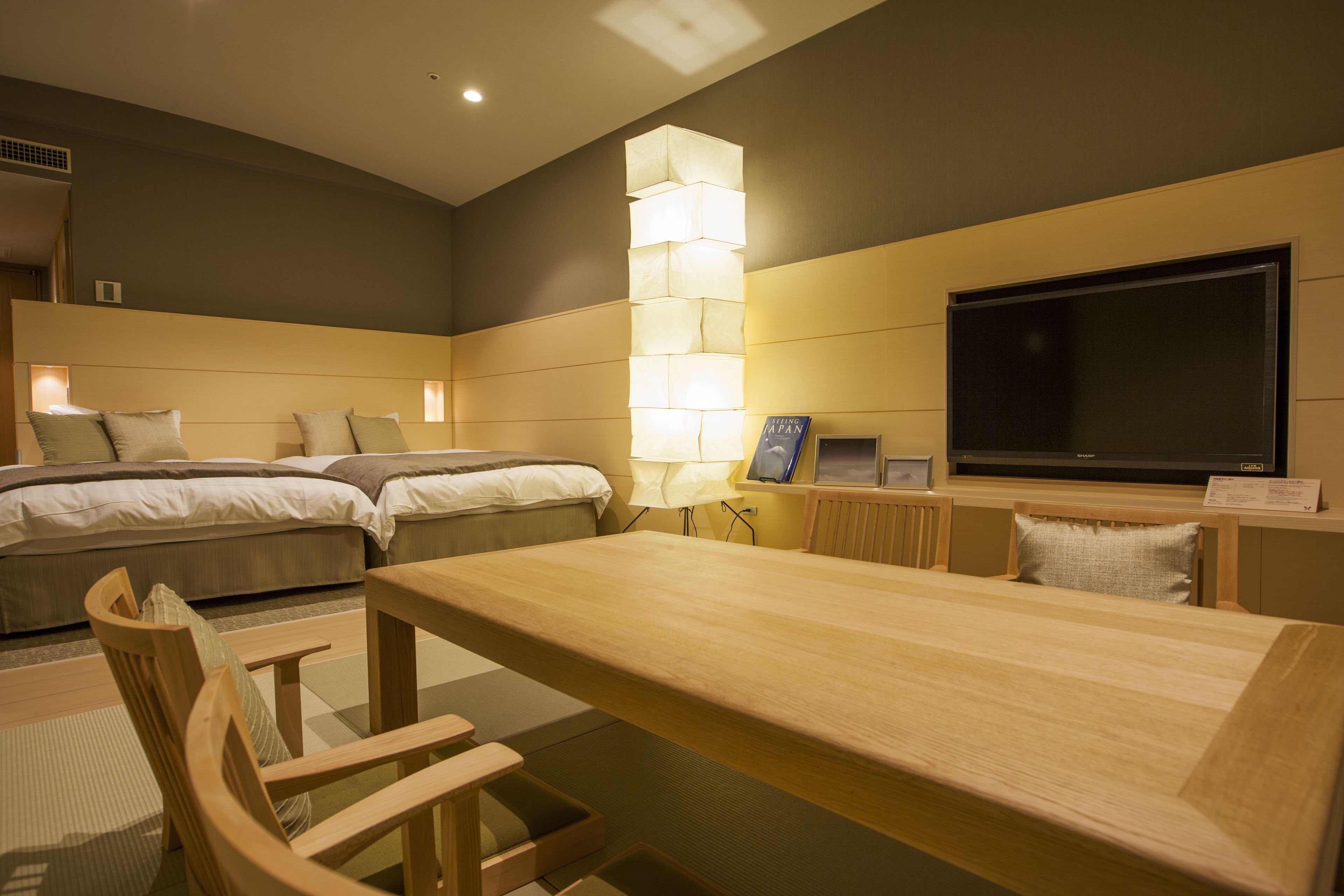 A hotel room with a large bed, a desk, and a TV.