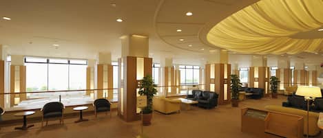Un hall d’entrée spacieux, doté d’espaces de détente, d’un comptoir d’accueil et de grandes fenêtres laissant entrer la lumière naturelle.