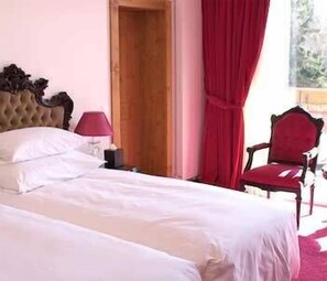 Un dormitorio con cama, mesita de noche, lámpara, silla y puerta de madera.