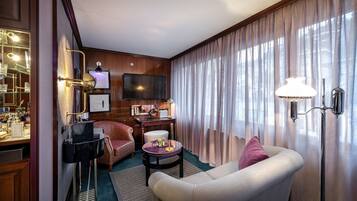 A well-furnished living room with a sofa, a round coffee table, a television, and a bar area with glassware.