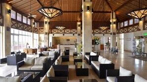 A spacious lobby with wicker sofas and tables, large windows, and a high ceiling with wooden beams. - Kanucha Bay Hotels & Villas (Nago)