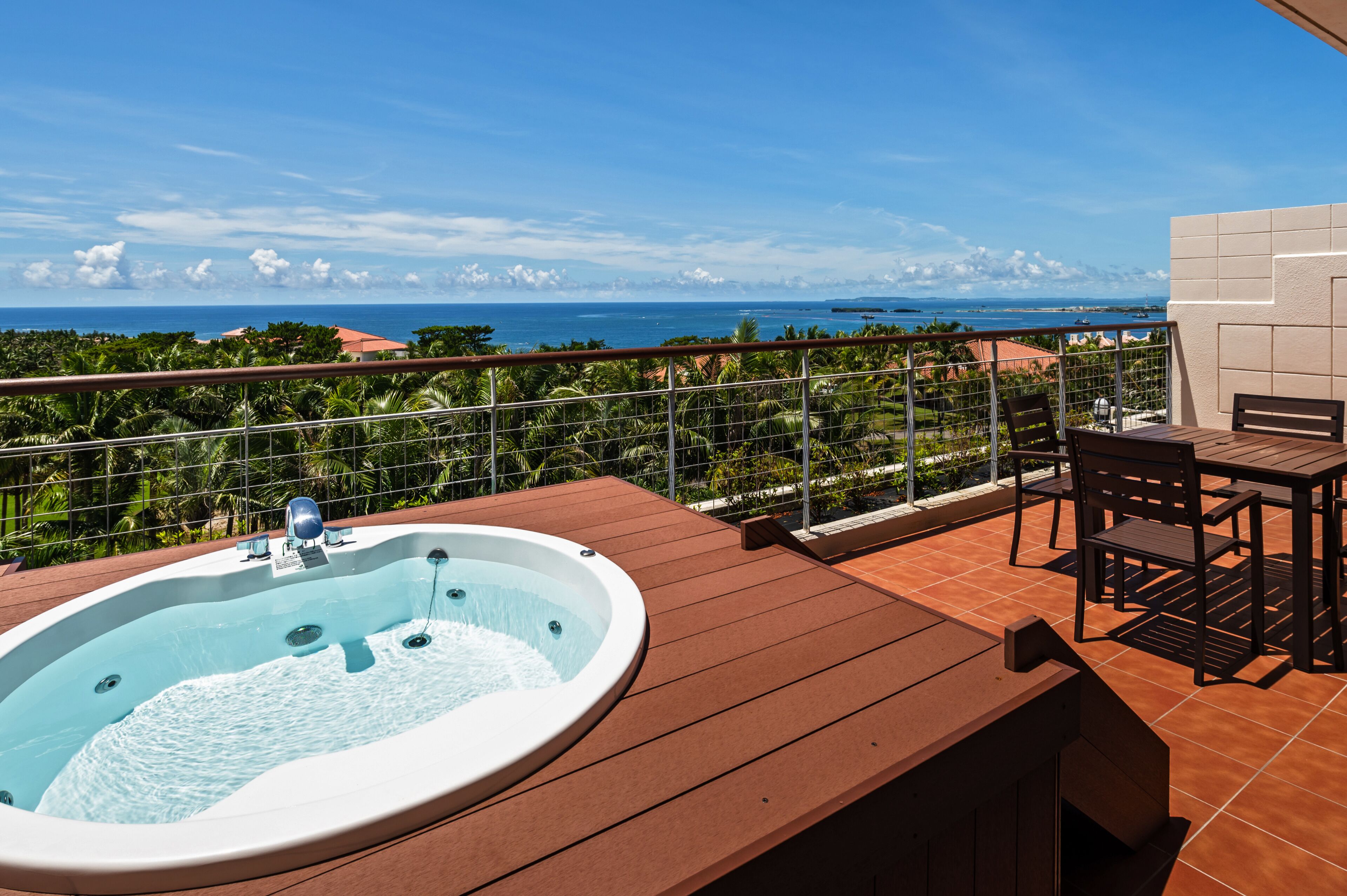 En balkon med jacuzzi, træterrasse og havudsigt.