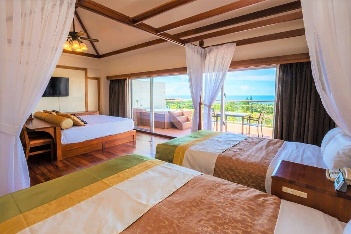 A hotel room with two beds, a balcony with a view, and a television.