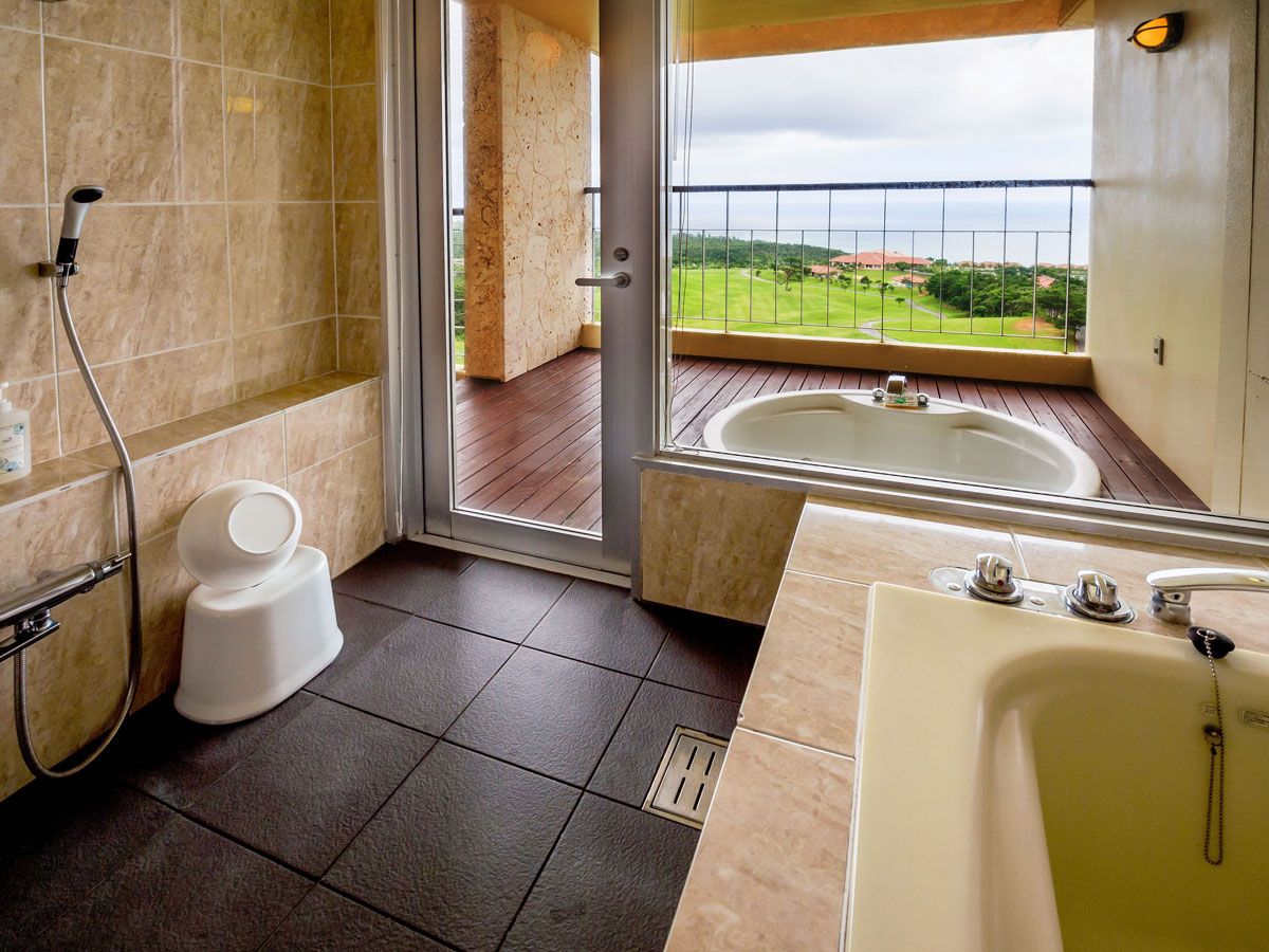 Un baño con ducha, inodoro y bañera, con vistas a un balcón y al paisaje.