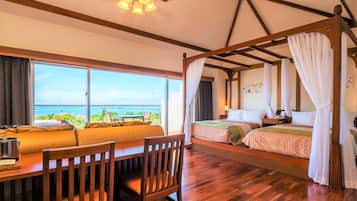 A room with a bed, a dining table, and a view of the ocean.
