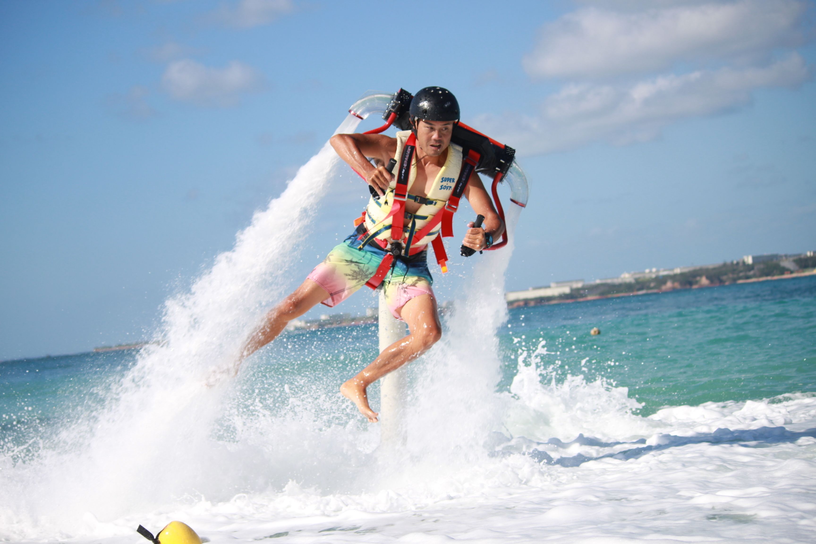 A person water skiing on a clear day with a cityscape in the background.