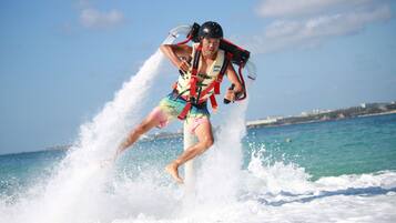 A person water skiing on a clear day with a cityscape in the background.