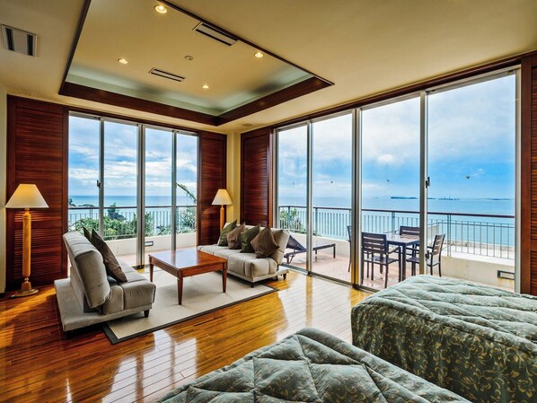 A spacious living area with a sofa, coffee table, and a view of the sea through large windows.