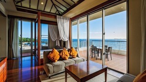 A spacious room with a large sliding glass door leading to a balcony with a view of the sea. - Kanucha Bay Hotels & Villas (Nago)