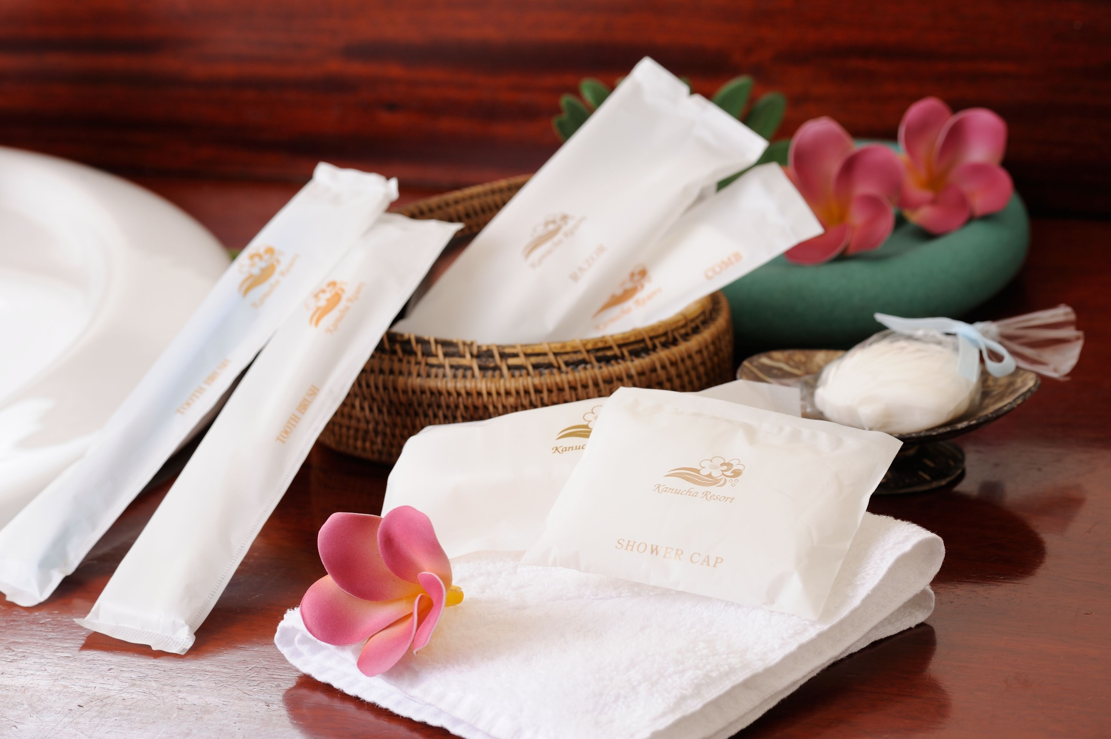 A wooden table with white towels, a shower cap, and a small bowl of soap.