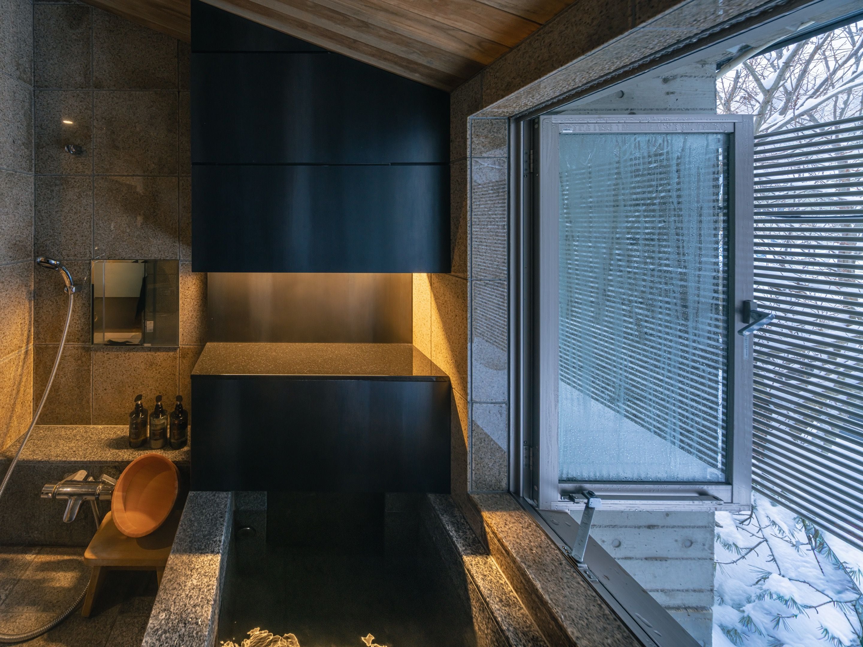 A modern bathroom with a large window, a built-in sink, and a shower area.