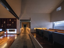 Un pasillo con piso de madera, una zona de bar con taburetes y una estantería con marcos y fotografías.