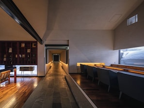 A hallway with a wooden floor, a bar area with bar stools, and a bookshelf with framed pictures.
