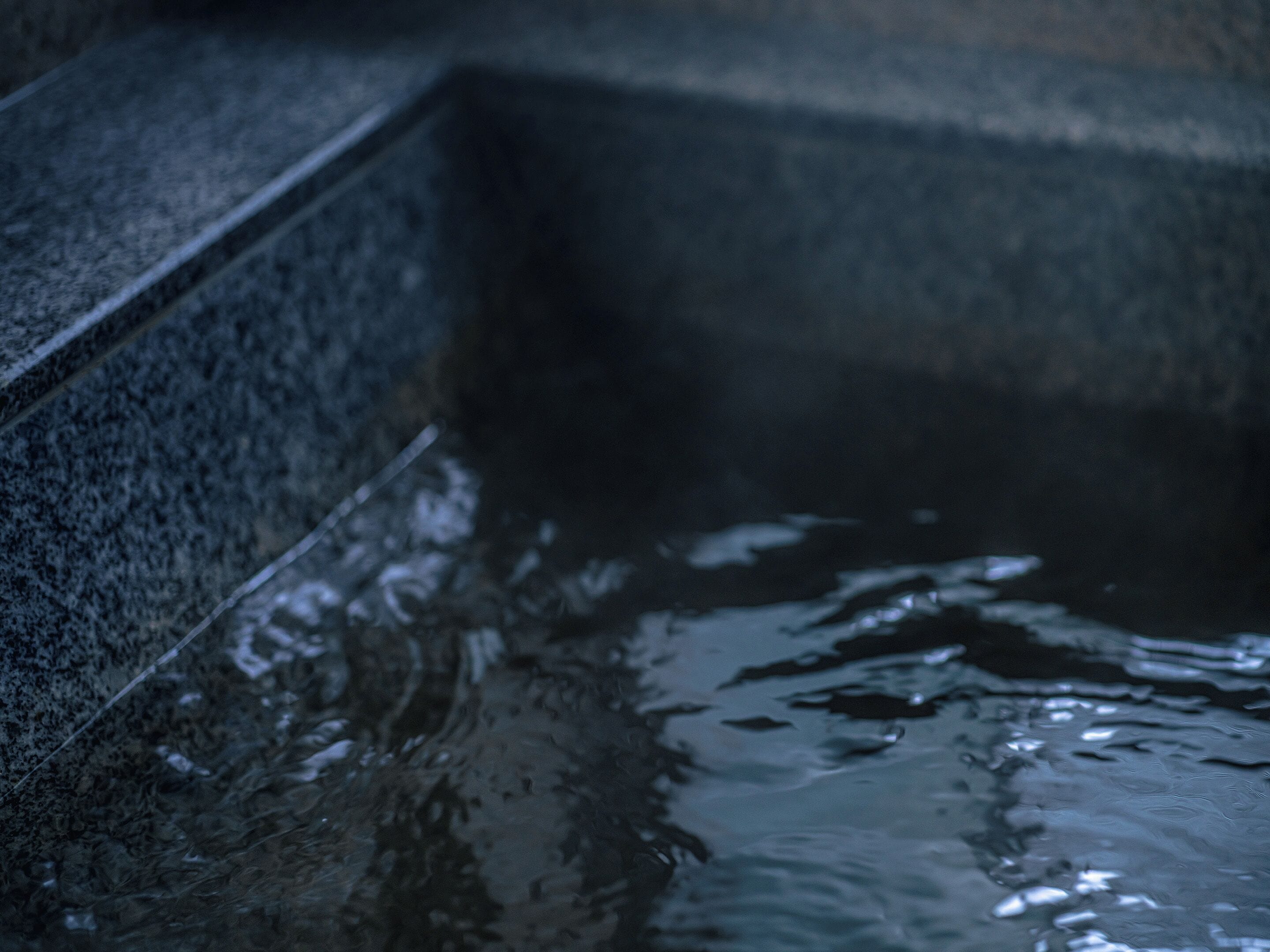 A close-up of a stone wall with water flowing down it.