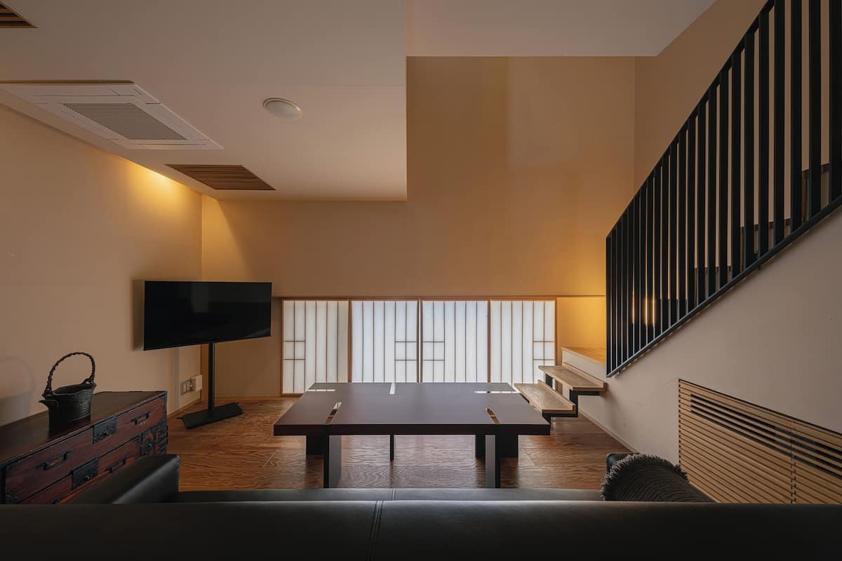 Una sala de estar moderna con un televisor de pantalla plana, una mesa de madera y una escalera.