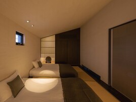 Un dormitorio moderno con dos camas, una ventana pequeña y una puerta corrediza.