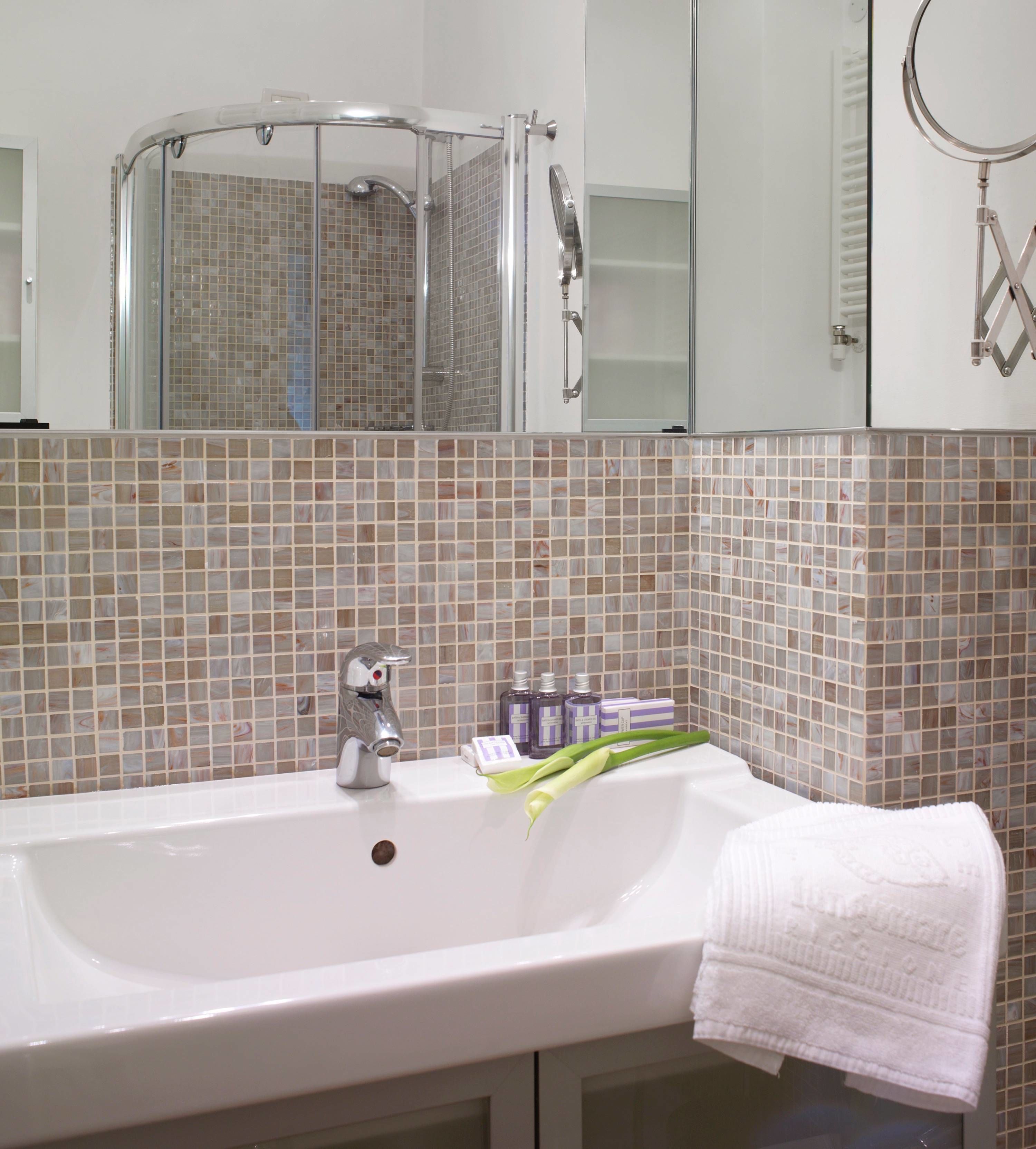 A bathroom with a white sink, a shower, and a mirror.