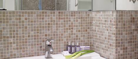A bathroom with a white sink, a shower, and a mirror.
