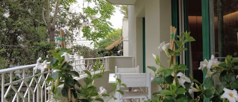 Ein Balkon mit weißen Stühlen, einem weißen Geländer und Grünpflanzen.