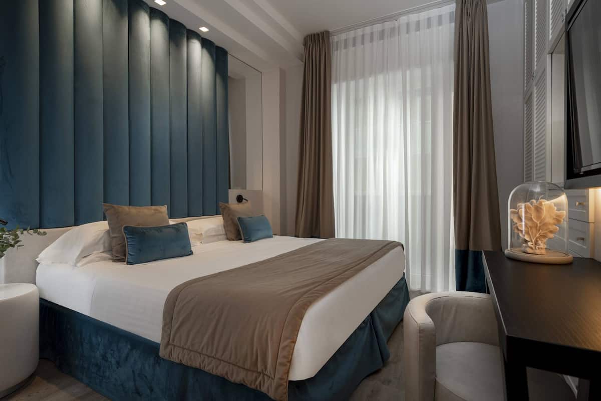 A modern hotel room with a large bed, a desk, and a television.