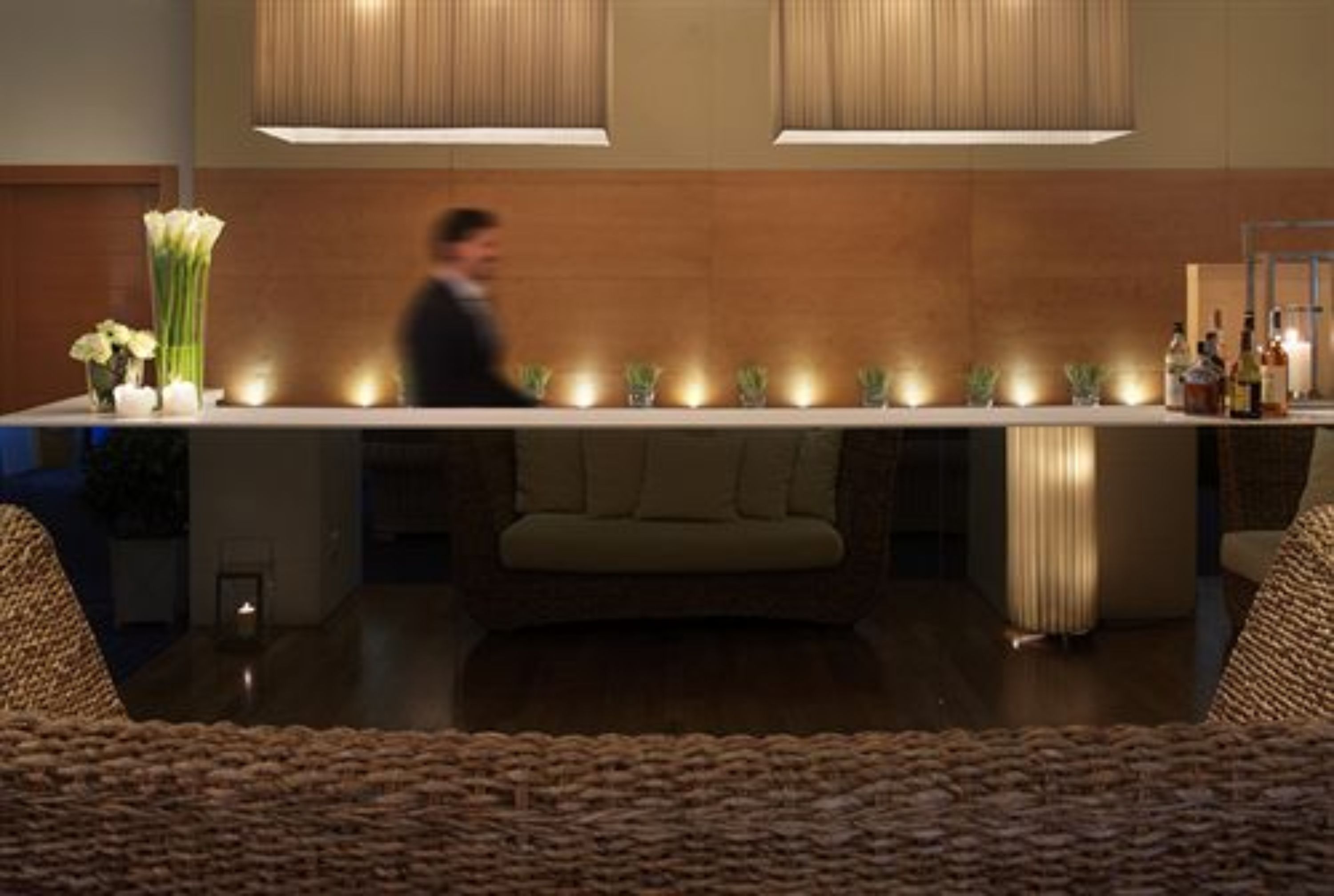 Un bar moderno con una barra larga, velas y un sofá.