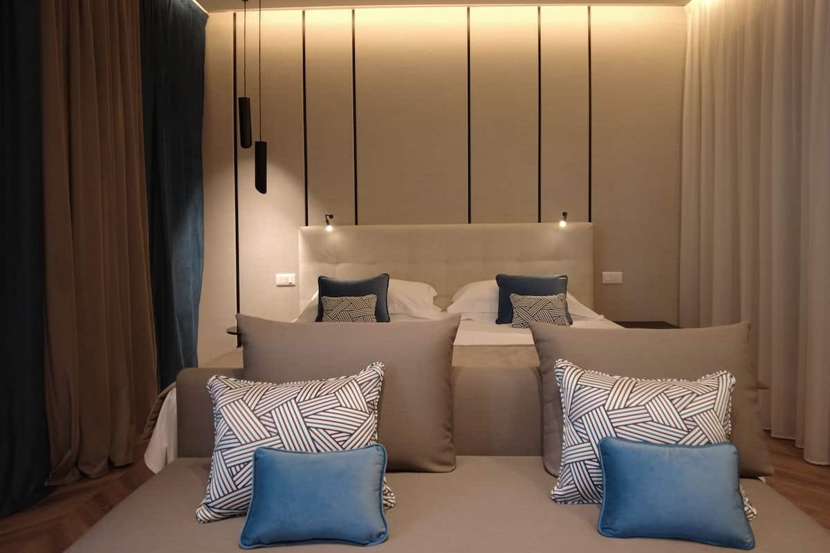 A modern bedroom with a large bed, two bedside tables, and a headboard with integrated lighting.