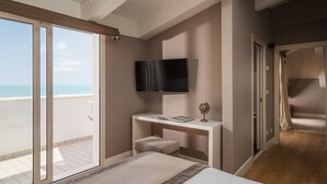 Een slaapkamer met balkon, een aan de muur bevestigde televisie, een bureau met een wereldbol en een bed.